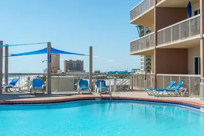 a swimming pool with blue chairs and a building at Sunrise Beach #2411 in Panama City Beach
