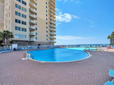 a swimming pool next to a building and the beach at Tidewater 314 NEW in Panama City Beach