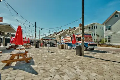 a patio with tables and red umbrellas on a street at Prominence on 30A by Panhandle Getaways in Watersound Beach
