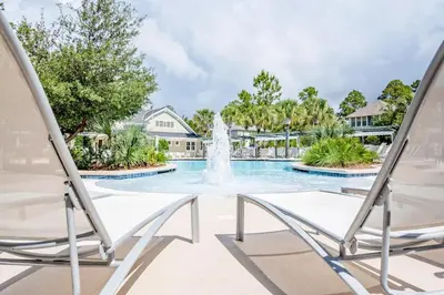 a fountain in the middle of a swimming pool with two chairs at Anchors Up in Watersound Beach