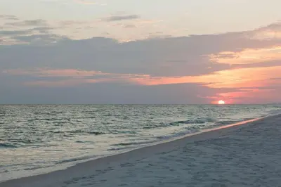 a sunset on a beach with the ocean at Sun and Sand in Inlet Beach