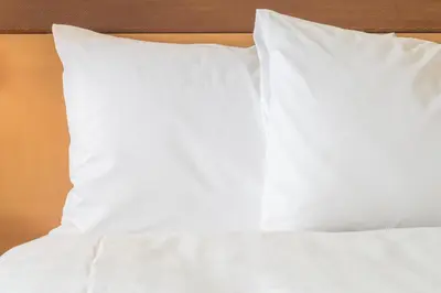 a bed with white sheets and pillows on it at Garner Hotel Panama City Beach Northeast by IHG in Panama City Beach