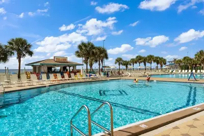 a large swimming pool with palm trees and a beach at The Summit 504 in Panama City Beach