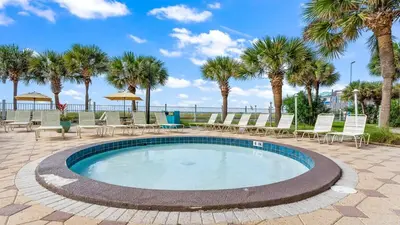 a swimming pool with chairs and palm trees at The Summit 620 in Panama City Beach