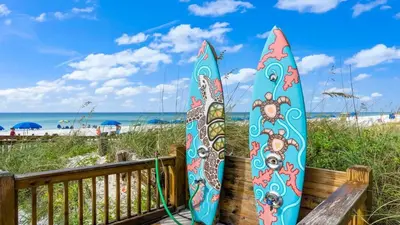 two surfboards are sitting on a bench at the beach at The Summit 620 in Panama City Beach