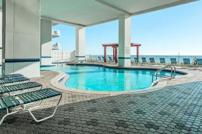 a swimming pool in a building with chairs and the ocean at Majestic Beach Towers 2-403 in Panama City Beach