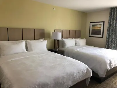 a hotel room with two beds with white sheets at Candlewood Suites - Panama City Beach Pier Park by IHG in Panama City Beach