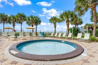 a swimming pool with chairs and palm trees at The Summit 228 in Panama City Beach