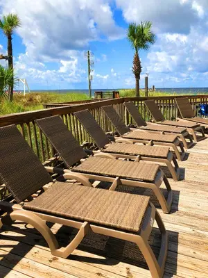 a row of chaise lounges on a boardwalk at the beach at Sunbird 1008W 'Hugo's Sugar Shack' in Panama City Beach