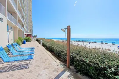 a couple of blue chairs on a sidewalk next to the beach at Majestic Beach Towers 1-609 in Panama City Beach