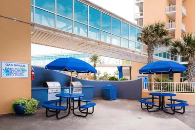 two tables and chairs with blue umbrellas in front of a building at Splash 303E in Panama City Beach