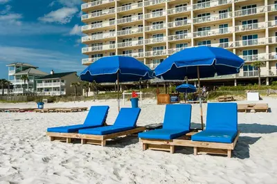 a group of blue chairs and umbrellas on a beach at Celadon 1902 