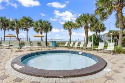 a swimming pool with chairs and palm trees at The Summit 220 in Panama City Beach