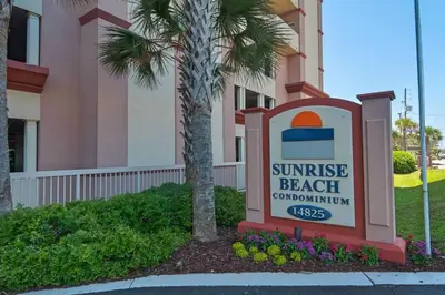 a sign in front of a building with a sunrise beach subdivision at Brightly Furnished Beachfront Condominium by Brightwild in Panama City Beach