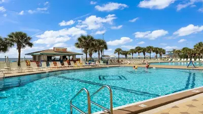 a large swimming pool with palm trees and a beach at The Summit 1121 in Panama City Beach