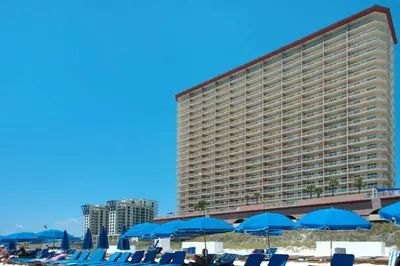 a large hotel with blue beach chairs and umbrellas at 8th Floor Gulf View Beachfront Condominium by Brightwild in Panama City Beach