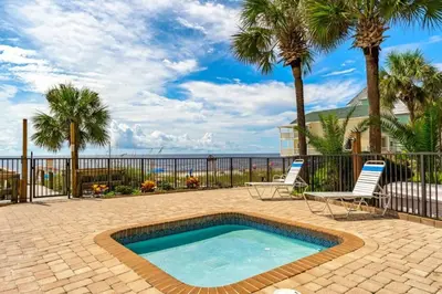 a swimming pool with two chairs and palm trees at Commodore 801 (3/3) in Panama City Beach