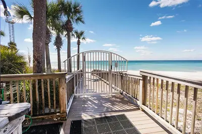 a wooden walkway to the beach with palm trees and the ocean at Hidden Dunes 1501 in Panama City Beach