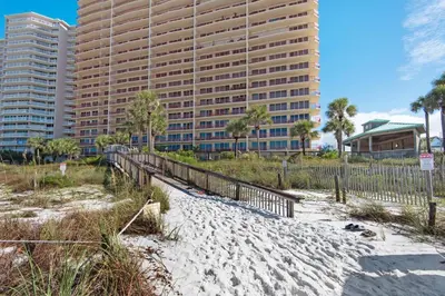 a sandy beach with a tall building in the background at Hidden Dunes 1501 in Panama City Beach