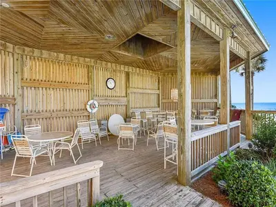 a wooden deck with tables and chairs and a clock at Hidden Dunes 1703 in Panama City Beach