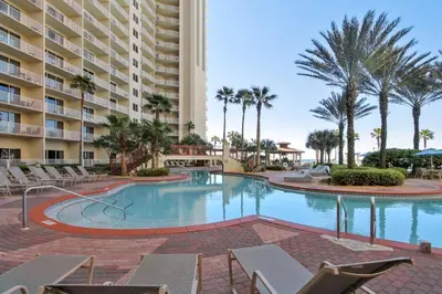 a swimming pool with chairs and a large building at Shores of Panama #2020 by Book That Condo in Panama City Beach