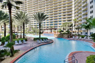 a large swimming pool with palm trees and a large building at Shores of Panama #1007 by Book That Condo in Panama City Beach