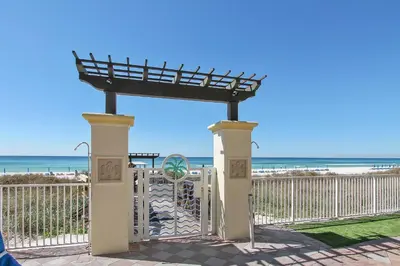 a gate at the beach with the ocean in the background at Shores of Panama #1119 by Book That Condo in Panama City Beach