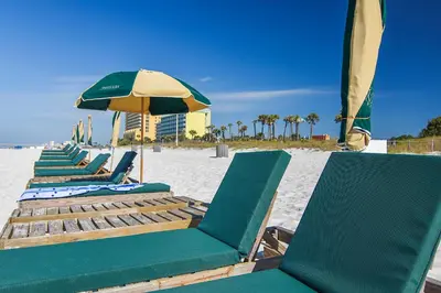 a row of lounge chairs and an umbrella on the beach at Grand Panama Beach Resort #406-1 by Book That Condo in Panama City Beach