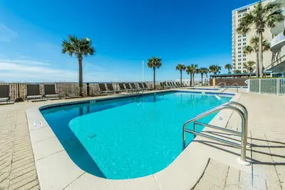 a large swimming pool with palm trees and a building at Ocean Villa 405 in Panama City Beach