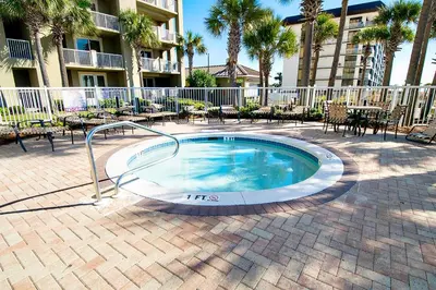 a swimming pool in a courtyard with tables and chairs at Grand Panama 1-409 in Panama City Beach