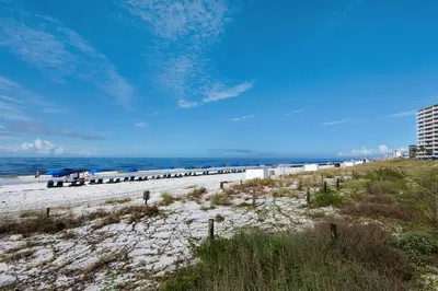 a beach with chairs and umbrellas and the ocean at Hidden Dunes 1401 in Panama City Beach