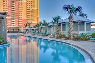 a swimming pool at a resort with palm trees and buildings at Calypso Tower 3 Beach Resort in Panama City Beach