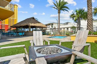 a fire pit in a park with two wooden chairs at Calypso Tower 3 Beach Resort in Panama City Beach