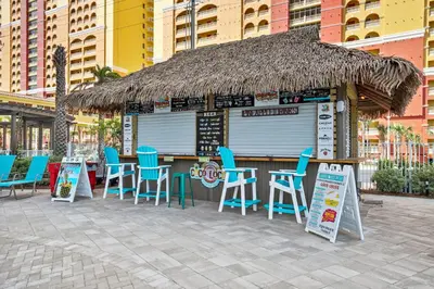 a bar with blue chairs and a straw roof at Calypso Beach Resort Tower 3 Rentals in Panama City Beach