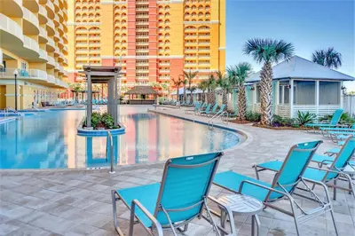 a swimming pool with blue chairs and a building at Tower 3 at Calypso Beach Resort in Panama City Beach