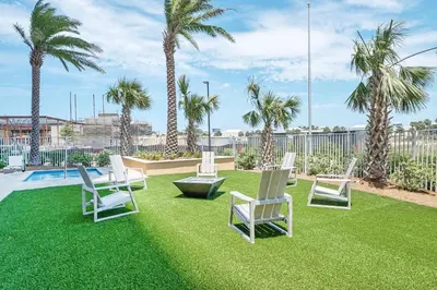 a group of chairs sitting on a lawn with palm trees at Calypso 3-205 in Panama City Beach