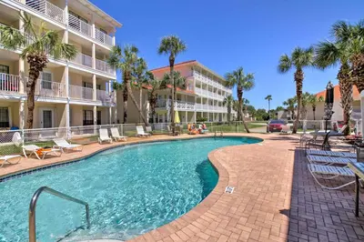 a swimming pool in front of a building with palm trees at PCB Resort Condo with Private Balcony and 3 Pools! in Panama City Beach