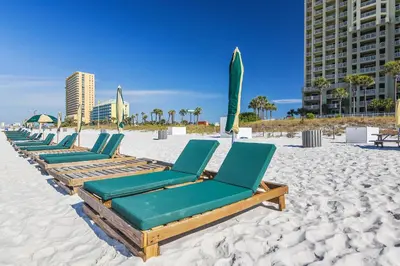 a row of chaise lounges on the beach at Grand Panama Beach Resort #908-1 by Book That Condo in Panama City Beach