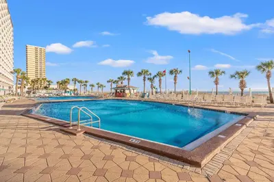 a swimming pool next to a beach with palm trees at The Summit 1208 in Panama City Beach