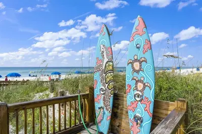 two surfboards are leaning against a fence at the beach at The Summit 626 in Panama City Beach
