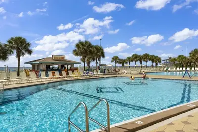 a large swimming pool with palm trees and a beach at The Summit 626 in Panama City Beach