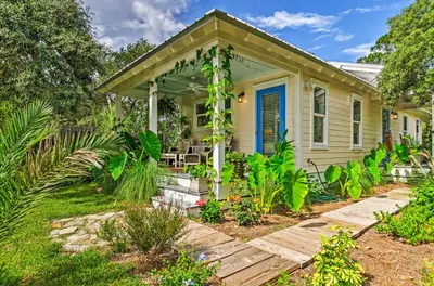 a small yellow house with a porch and plants at Tropical Studio quarter Mi to Public Beach Access! in Santa Rosa Beach