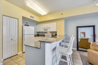 a kitchen with a white refrigerator and two white chairs at Shores of Panama #1725 at Book That Condo in Panama City Beach