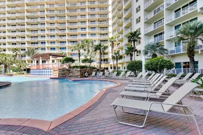 a pool with lounge chairs and a large building at Shores of Panama #1727 at Book That Condo in Panama City Beach