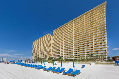 a row of chairs on the beach in front of a hotel at Calypso 1-2208 East in Panama City Beach