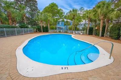 a swimming pool in a yard with palm trees at A Wave From It All in Santa Rosa Beach