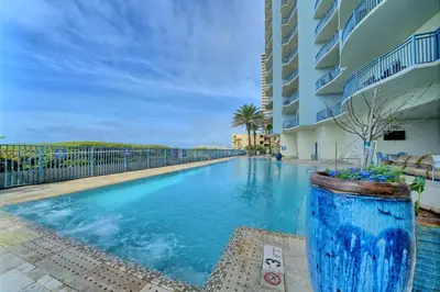 a large blue swimming pool next to a building at Sterling Breeze - Cozy Beachfront One Bedroom Condo in Panama City Beach