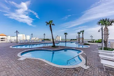 a large swimming pool with palm trees in a resort at Luxurious 4 Bedroom Condo! Gulf Views! Sleeps 10 & Easy Beach Access! by Dolce Vita Getaways PCB in Panama City Beach