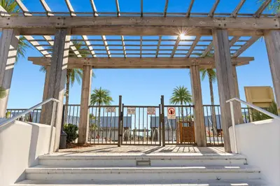 a wooden gate with palm trees in the background at Prominence on 30A Rentals by Panhandle Getaways in Watersound Beach