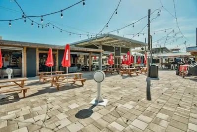 a patio with wooden benches and red umbrellas at Happily Eva After at Prominence 30A in Inlet Beach